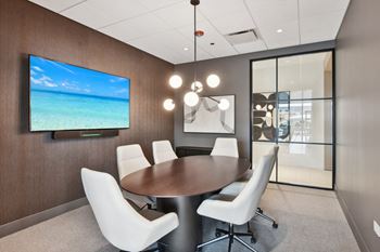 A conference room with a table and chairs and a television